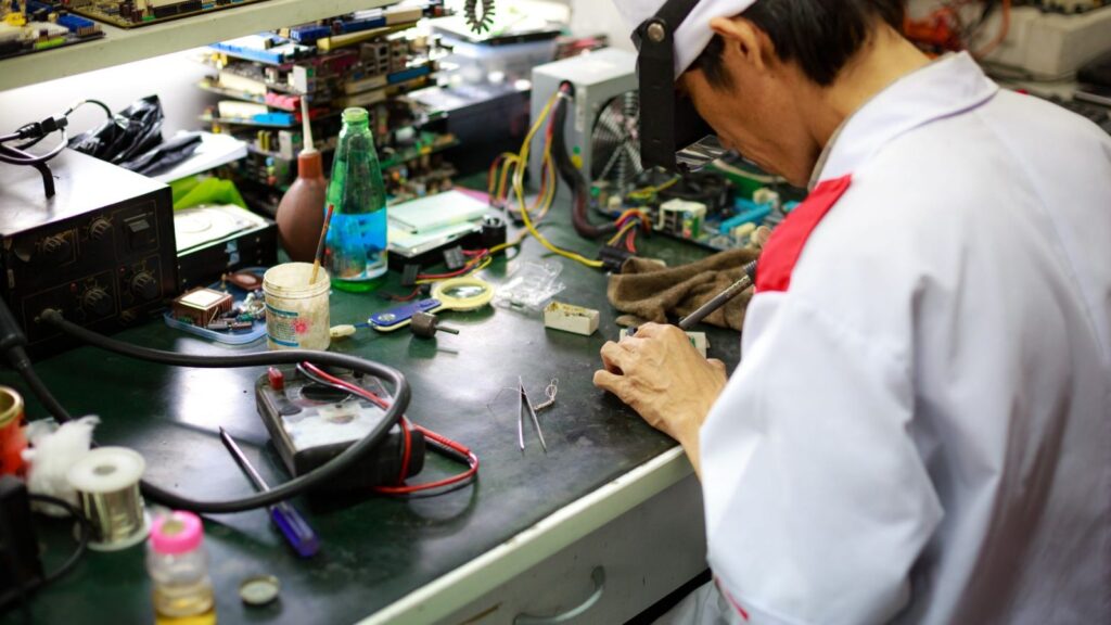 A technician inspects the board of home audio equipment
